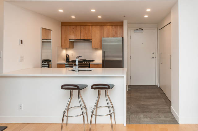 Furnished kitchen with white countertops and wooden cabinets, hardwood floors. - 1503 - 198 Aquarius Mews, Vancouver Downtown