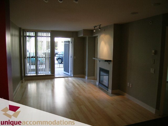 Spacious living room with hardwood floors, large windows, and a cozy den area. - 104 - 175 W. 1st. Street, North Vancouver