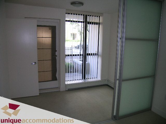 Spacious living room with sliding glass door leading to balcony, featuring a modern design and light green walls.