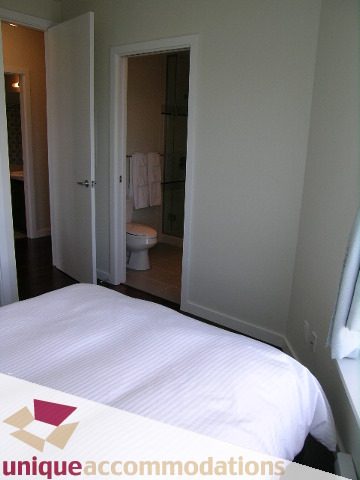 Bright bedroom with white bedding and bathroom access. - 411 - 2055 Yukon Street, Vancouver West Side