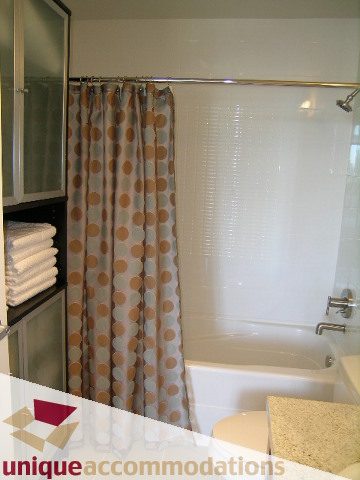Bathroom with white bathtub, polka dot shower curtain, granite countertop. - 411 - 2055 Yukon Street, Vancouver West Side