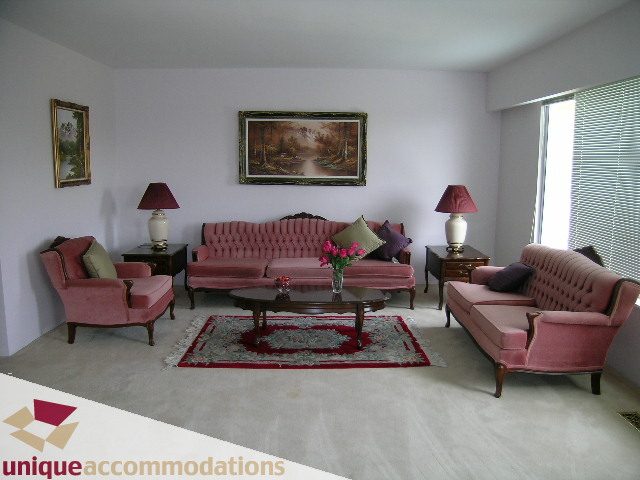 Furnished living room with pink furniture, red rug, and large window. - 94 Bonnymuir Drive, West Vancouver