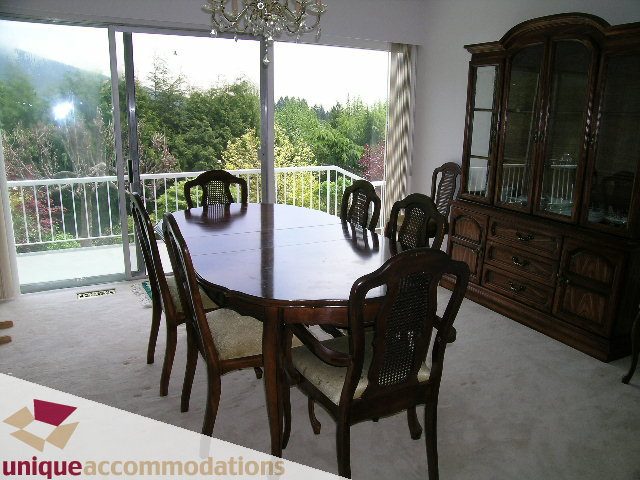 Furnished dining room with wooden table, chairs, and china cabinet, overlooking a scenic view. - 94 Bonnymuir Drive, West Vancouver