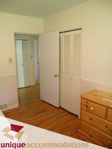 Bright bedroom with hardwood floors and a dresser, featuring a closet with louvered doors. - 94 Bonnymuir Drive, West Vancouver