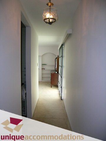 Bright hallway with arched doorway and wall sconces, leading to a cozy corner with a small table. - 94 Bonnymuir Drive, West Vancouver
