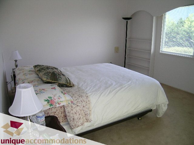 Furnished bedroom with floral bedding and a floor lamp. - 94 Bonnymuir Drive, West Vancouver