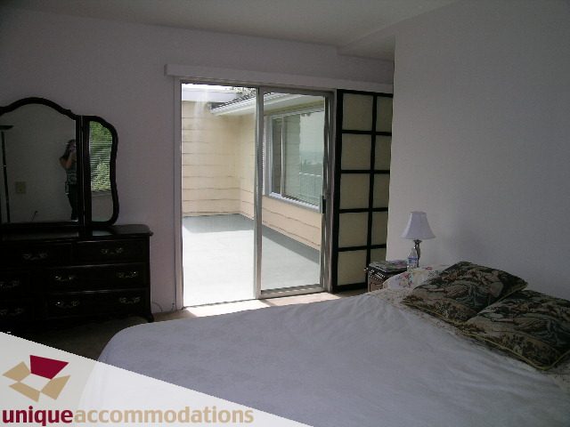 Bright bedroom with large window, white bedding, and dark furniture. - 94 Bonnymuir Drive, West Vancouver