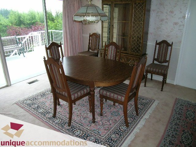 Furnished dining room with wooden table, striped chairs, and patterned rug. - 94 Bonnymuir Drive, West Vancouver