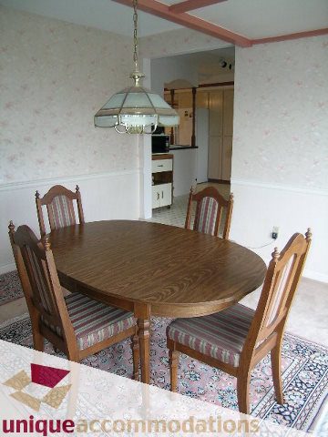 Bright dining area with wooden table, striped chairs, and a hanging light fixture. - 94 Bonnymuir Drive, West Vancouver