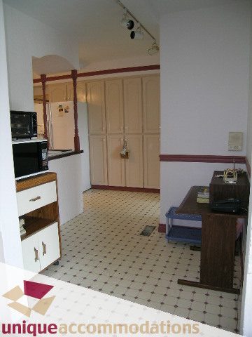 Bright kitchen with white cabinets, tiled floor, and a microwave. - 94 Bonnymuir Drive, West Vancouver