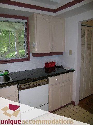 Bright kitchen with white cabinets, black countertops, and hardwood floors. - 94 Bonnymuir Drive, West Vancouver