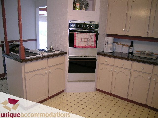 Bright kitchen with white cabinets, dark countertops, and a checkered towel on the oven. - 94 Bonnymuir Drive, West Vancouver