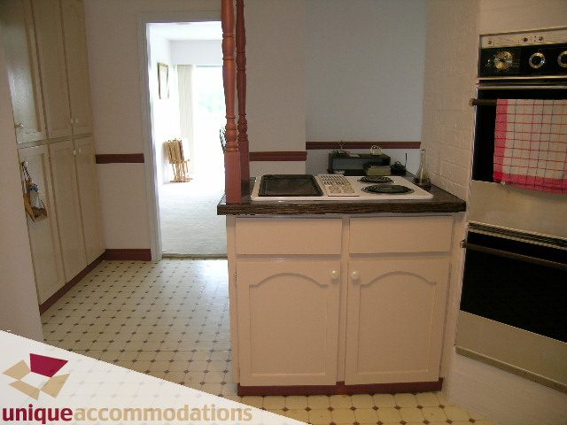 Bright kitchen with white cabinets, tiled floor, and a stove top oven. - 94 Bonnymuir Drive, West Vancouver