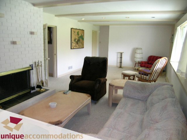 Living room with a fireplace, patterned couch, and wooden coffee table. - 94 Bonnymuir Drive, West Vancouver