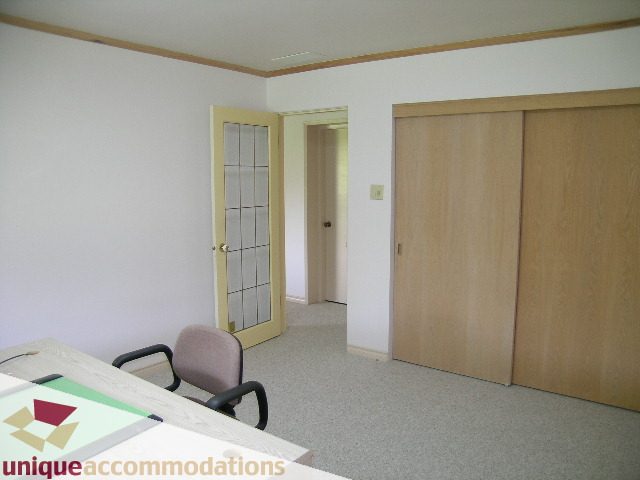 Spacious living room with wooden sliding doors and a desk corner. - 94 Bonnymuir Drive, West Vancouver