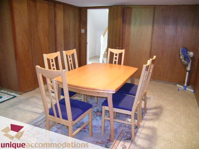 Dining area with wooden chairs and table, tiled floor, and wooden walls. - 94 Bonnymuir Drive, West Vancouver