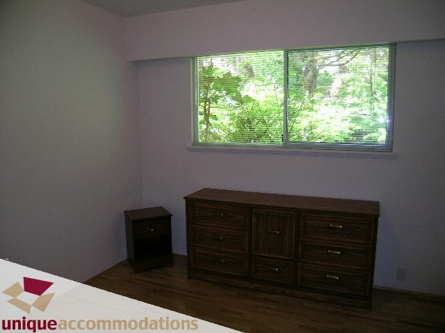 Bright bedroom with hardwood floors and large window view of greenery. - 94 Bonnymuir Drive, West Vancouver