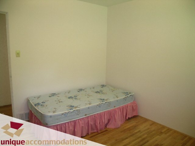 Bright bedroom with twin beds, hardwood floors, and floral bedding. - 94 Bonnymuir Drive, West Vancouver