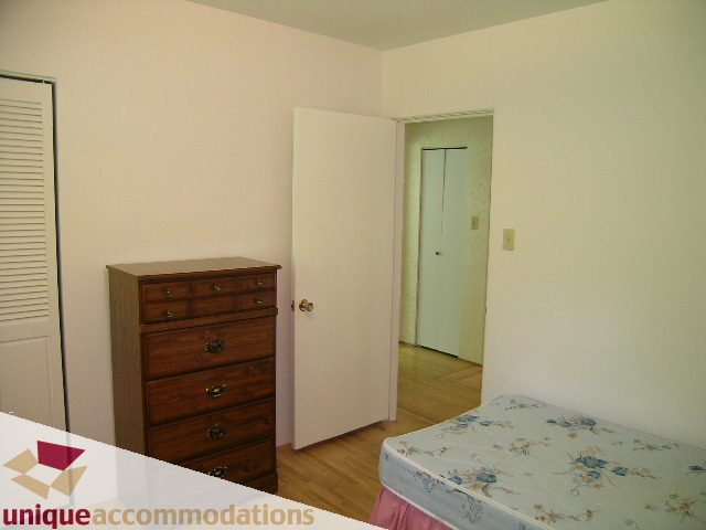 Bright bedroom with hardwood floors and a floral bedspread. - 94 Bonnymuir Drive, West Vancouver