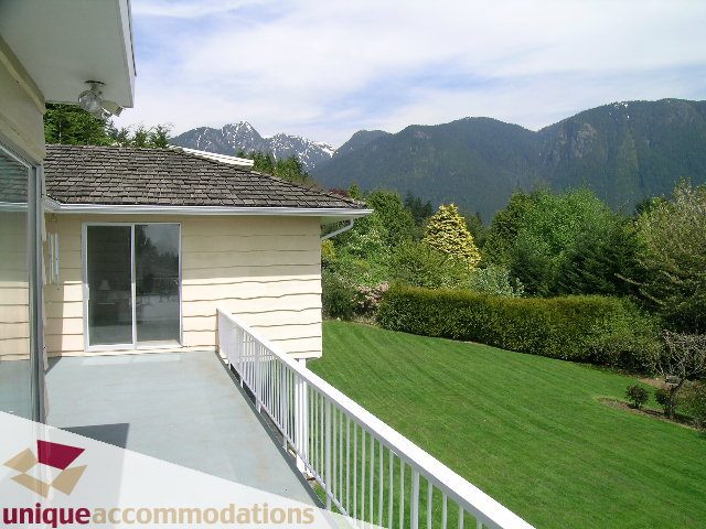 Bright living room with a view of mountains and a well-maintained lawn. - 94 Bonnymuir Drive, West Vancouver