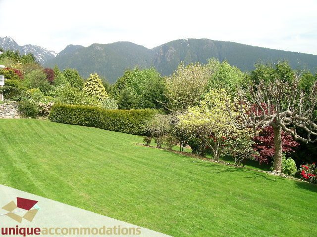 Spacious living room with lush green lawn and mountain view. - 94 Bonnymuir Drive, West Vancouver