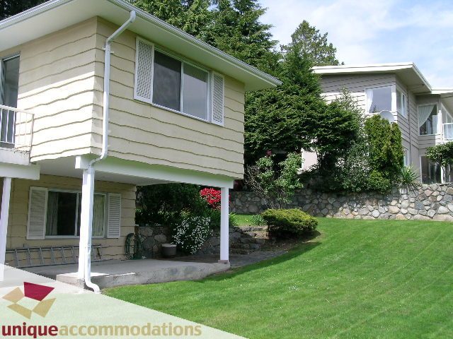 Spacious living room with large windows and stone wall. - 94 Bonnymuir Drive, West Vancouver