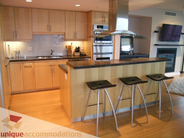 Modern kitchen with granite countertops, hardwood floors, and a sleek bar area. - 602 - 1233 West Cordova Street, Vancouver Downtown