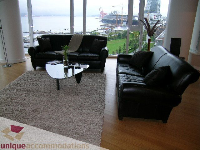 Spacious living room with hardwood floors, a large city view, and a cozy black leather sofa set. - 602 - 1233 West Cordova Street, Vancouver Downtown