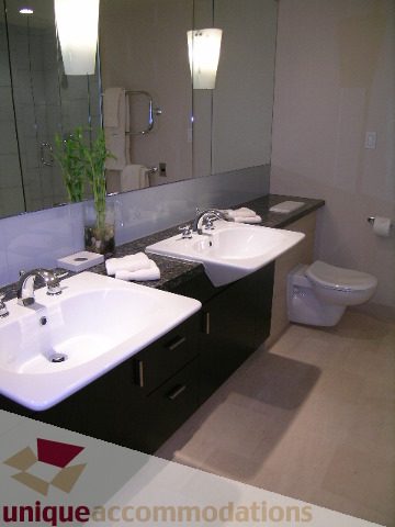 Spacious bathroom with double sinks, black countertops, and a large mirror. - 602 - 1233 West Cordova Street, Vancouver Downtown