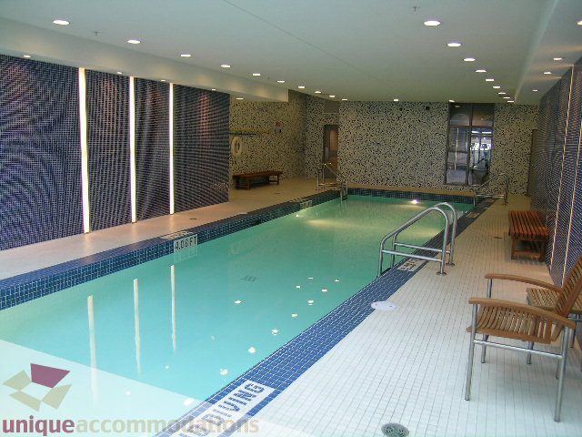 Spacious, modern 2-bedroom + den condo with a luxurious indoor pool and spa area, featuring tiled walls and floors.