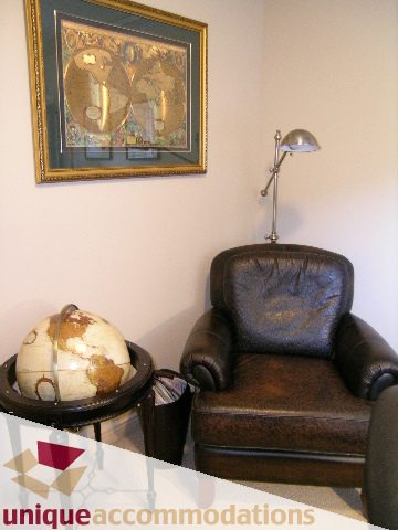 Furnished living room with leather armchairs, globe, and wall art. - 1003 Kilmer Road, North Vancouver