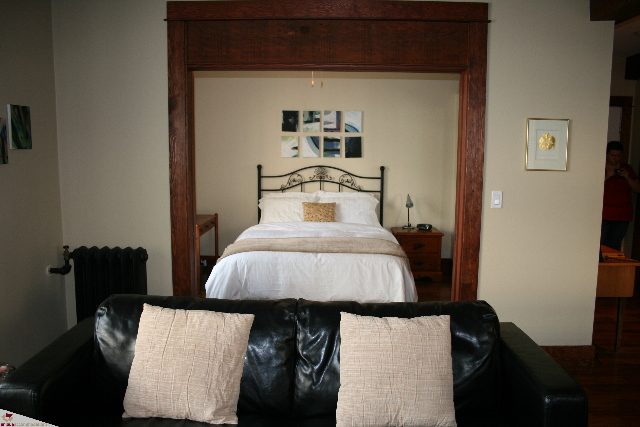 Furnished 1-bedroom with a cozy bed, dark wood accents, and a leather couch. - 30 - 777 Burrard Street, Vancouver Downtown