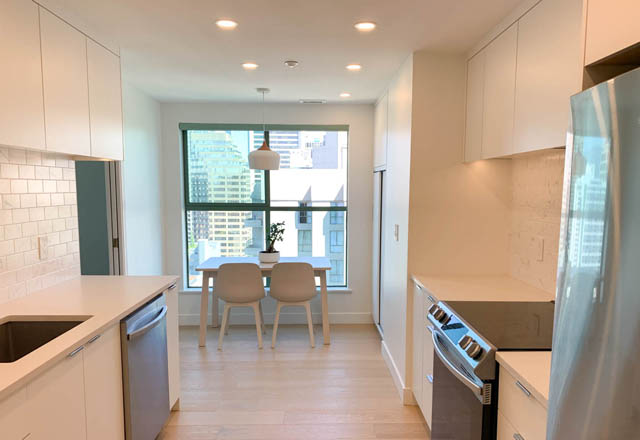 Bright kitchen with white cabinets, hardwood floors, and a city view. - 1901 - 909 Burrard Street, Vancouver Downtown