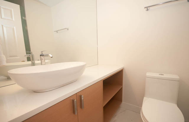 Bright bathroom with white sink, modern faucet, and wooden cabinets. - 1901 - 909 Burrard Street, Vancouver Downtown
