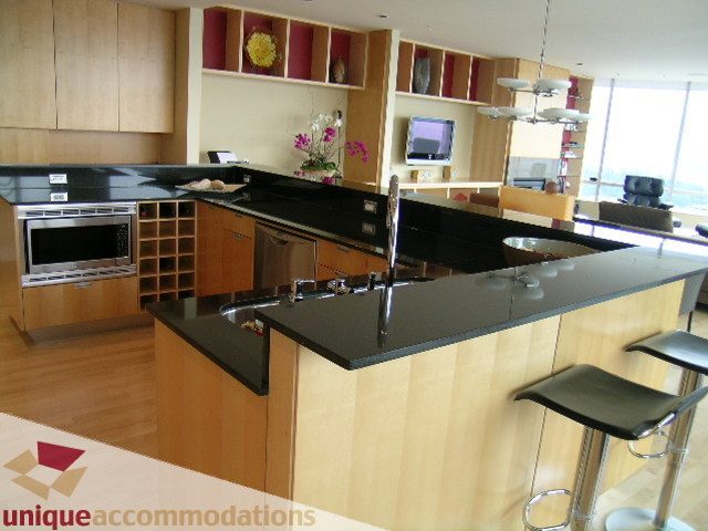 Modern kitchen with sleek black countertops, wooden cabinets, and a city view. - 2401 - 1077 W. Cordova Street, Vancouver Downtown