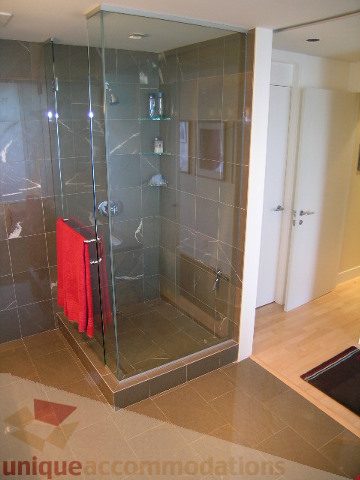 Spacious bathroom with glass shower, modern tile, and wooden vanity. - 2401 - 1077 W. Cordova Street, Vancouver Downtown