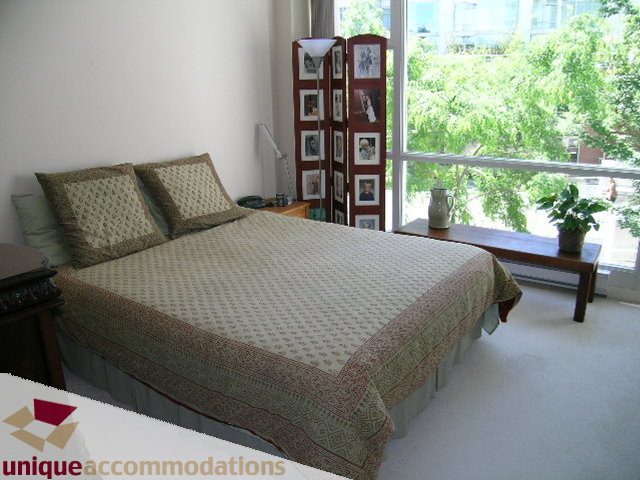 Bright bedroom with city view and wooden furniture. - 183 Aquarius Mews, Vancouver Downtown