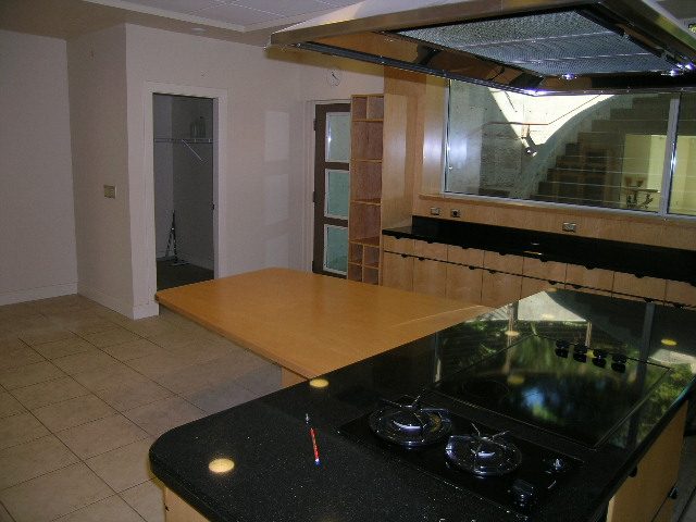 Modern kitchen with black countertops and wooden cabinets, featuring a large window with a city view. - 947 Huntingdon Crescent, North Vancouver