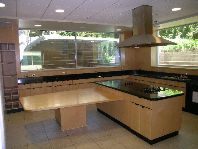 Modern kitchen with light wood cabinets, black countertops, and large windows offering a city view. - 947 Huntingdon Crescent, North Vancouver