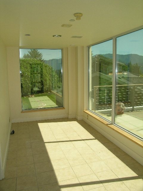 Spacious sunroom with large windows, tiled floor, and scenic mountain view. - 947 Huntingdon Crescent, North Vancouver