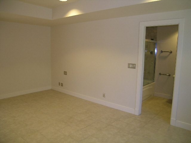 Spacious bathroom with walk-in shower and dual sinks, featuring beige tile flooring and white walls. - 947 Huntingdon Crescent, North Vancouver