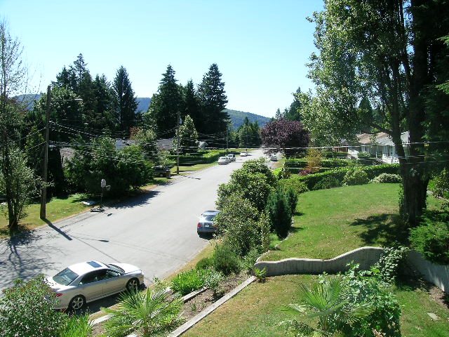 Spacious living room with lush greenery and a serene view of the mountains. - 947 Huntingdon Crescent, North Vancouver