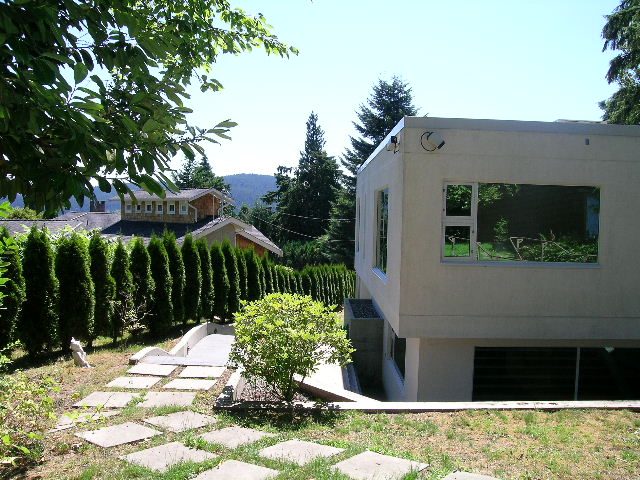 Modern 4-bedroom house with unique architectural design, featuring large windows and a serene garden setting.