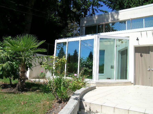 Spacious living room with large glass windows, modern furnishings, and a cozy patio. - 947 Huntingdon Crescent, North Vancouver