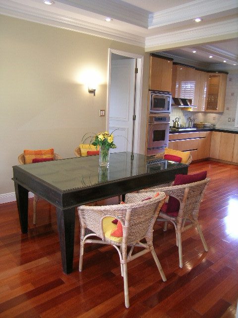 Furnished dining area with hardwood floors, modern kitchen in background. - 1233 11th Street, West Vancouver