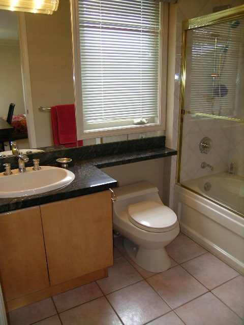 Bathroom with black countertops, wooden cabinets, and a shower/tub combo. - 1233 11th Street, West Vancouver