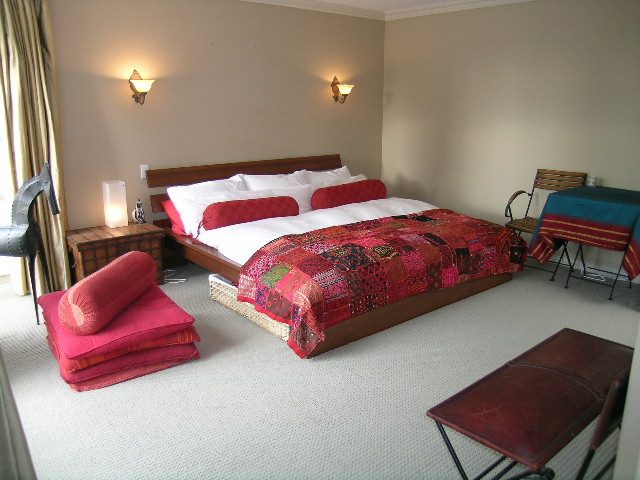 Furnished bedroom with two double beds, vibrant red bedding, and wall sconces. - 1233 11th Street, West Vancouver
