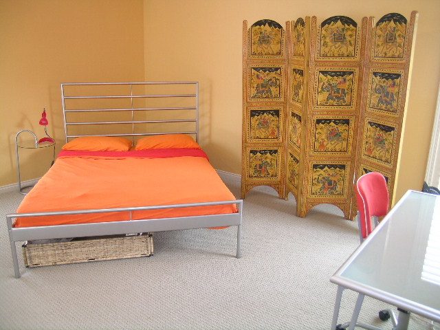 Bright bedroom with orange bedding and decorative screen, furnished and cozy. - 1233 11th Street, West Vancouver