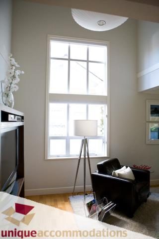Bright living room with hardwood floors and a large window, featuring a modern lamp and a cozy corner. - 2555 W 2nd Avenue, Vancouver West Side