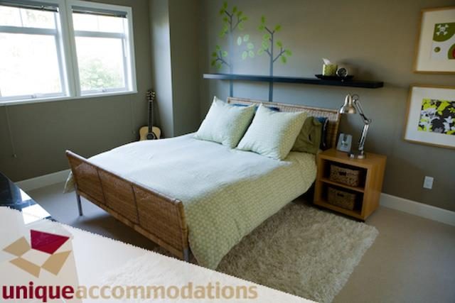 Furnished bedroom with a neatly made bed, light green pillows, and a guitar in the corner. - 2555 W 2nd Avenue, Vancouver West Side